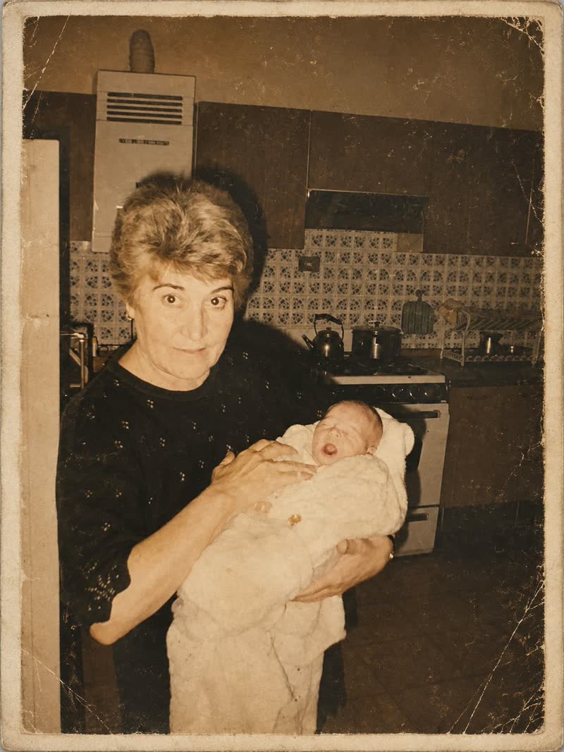 Giuseppina, la abuela de Zahira y Danisa, con un recién nacido en brazos en su cocina